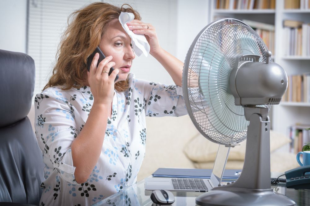 Woman,Suffers,From,Heat,While,Working,In,The,Office,And