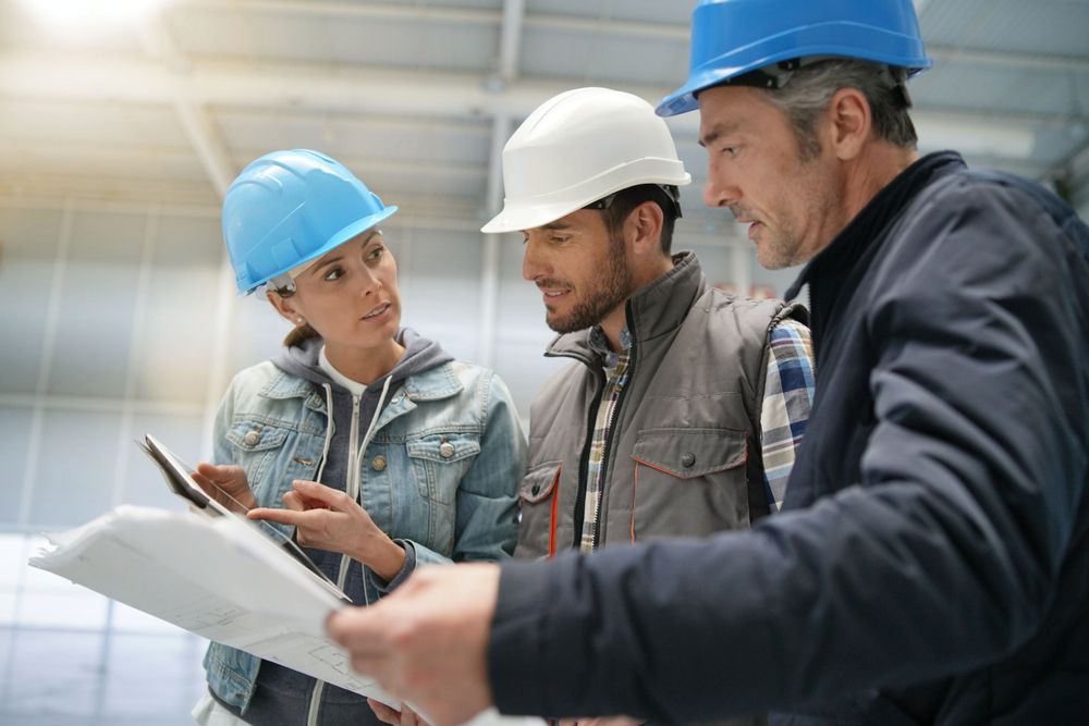 Team,Of,Construction,Workers,Talking,In,Empty,Warehouse